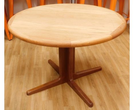 A Danish teak extending dining table, the circular top with shaped edge on a central column and tapering feet, one loose leaf