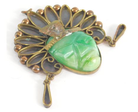 A Mexican jade set pendant, the pendant in the form of a warrior, with looped brass effect headdress, with a carved jade cent