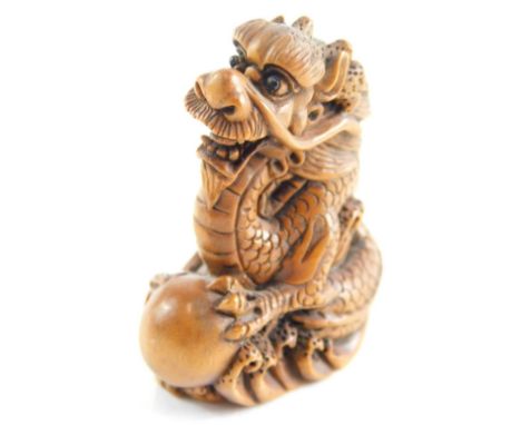 A Japanese wooden netsuke, carven in the form of a dragon with a ball, 5cm high.