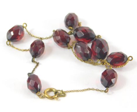 A faceted cherry amber necklace, with ten faceted beads, on a gold coloured chain, unmarked, 32cm long overall, 5g all in.