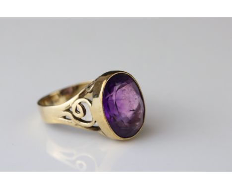 Amethyst 9ct yellow gold ring, the oval mixed cut diamond measuring approx 15mm x 11.5mm, collet setting, openwork scroll mou