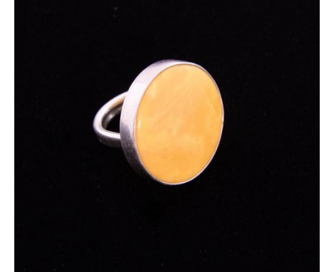 Modernist circular plaque ring, set with large yellow amber stone in silver mount  