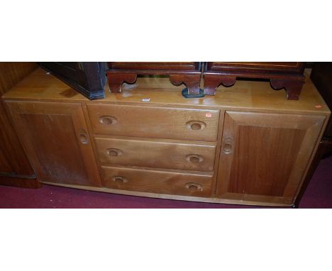 An Ercol light elm sideboard, having three central drawers flanked by conforming cupboard doors, on roller castors (with sun-
