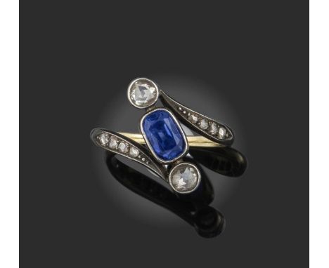 A sapphire and diamond three stone ring, set with a cushion-shaped sapphire flanked by rose-cut diamonds within further rose-