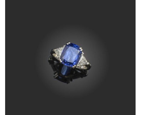 A tanzanite and diamond three stone ring, the cushion-shaped tanzanite flanked with triangular-shaped diamonds in platinum, s
