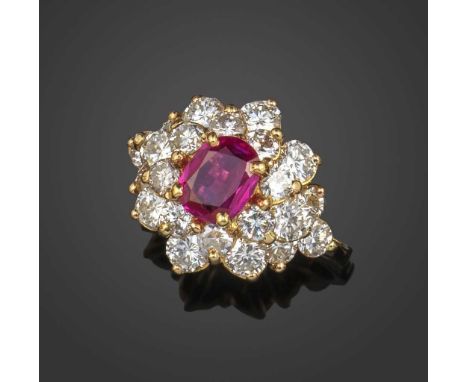 A ruby and diamond cluster ring, the oval ruby in raised yellow gold setting, within surround of graduated round brilliant-cu