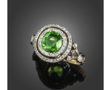 An early 20th century demantoid garnet and diamond cluster ring, the cushion-shaped demantoid weighing approximately 1.30cts,