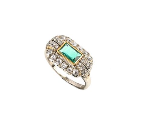 An emerald and diamond ring, the emerald-cut emerald set in yellow gold, within a geometric surround of round brilliant-cut d