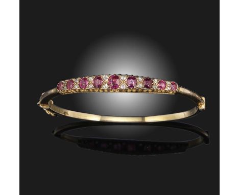 A Victorian ruby and diamond bangle, of hinged design, set with a row of graduated cushion-cut rubies alternating with old ci