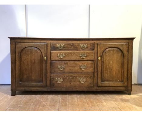 An 18th century oak country dresser, the twin plank rectangular top over four graduated drawers, flanked ty two fielded panel