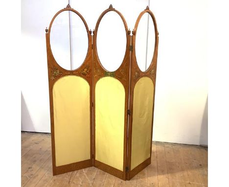 A Sheraton Revival painted satinwood room divider screen, c. 1900, each oval glazed and silk-upholstered panel surmounted by 