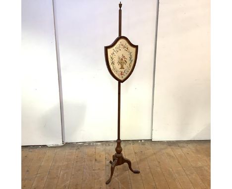 A George III mahogany firescreen, early 19th century, the rise and fall banner of shield form inset with a silk embroidered p