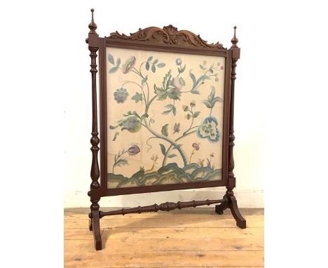An Edwardian mahogany firescreen, the frame surmounted by a scroll-carved pediment and two turned finials above two turned an