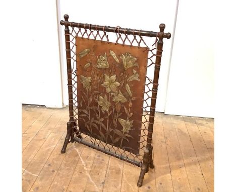 An early 20th century firescreen, the faux-bamboo stained beech frame enclosing a floral-embossed leather panel, raised on ou