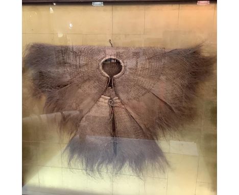 A Chinese woven coconut fibre raincoat or cloak, c. 1900, strikingly mounted in a box frame with gilt-tile background, signed