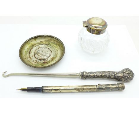 A silver topped inkwell, a pen, a silver dish and a button hook