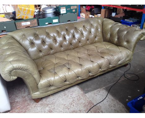 A green leather Chesterfield sofa with scroll arms. 