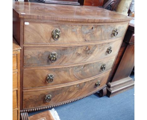 A REGENCY MAHOGANY CHEST OF DRAWERS fitted four long drawers with stamped brass ring handles, on gadrooned base and scrolled 