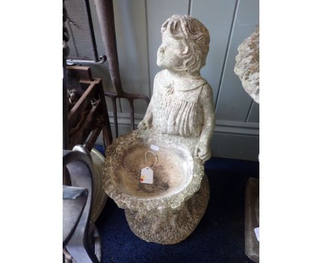 A RECONSTITUTED STONE BIRD BATH the basin of tree stump form, with a girl standing behind 54cm high