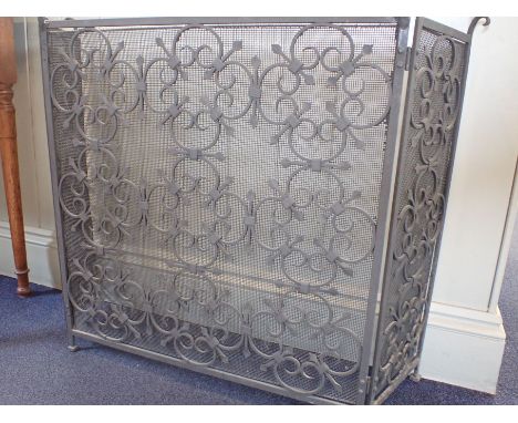 A WROUGHT IRON AND MESH FIRE SCREEN, OF TRIPTYCH FORM with brass finials, the central panel 63cm wide