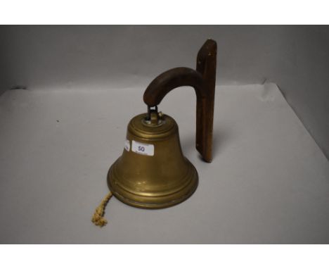 A pub or tavern style cast brass bell with oak bracket