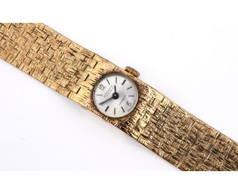 A LADY'S 9CT GOLD WRISTWATCH the circular dial with Arabic numerals at 12 and 6 o'clock and with baton numerals, on an integr