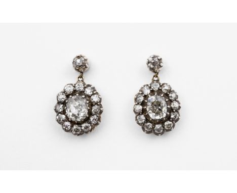 A PAIR OF VICTORIAN DIAMOND CLUSTER EARRINGS each earring mounted with an oval old-cut diamond in collet setting, within a su