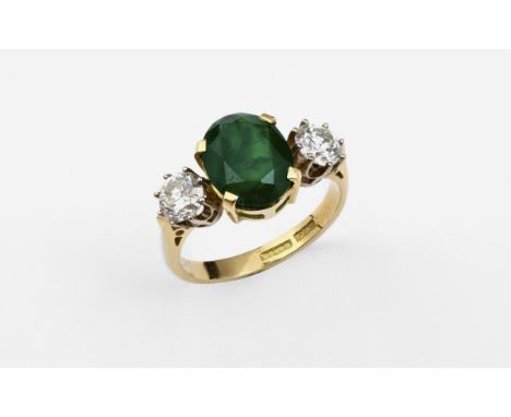 AN EMERALD AND DIAMOND THREE STONE RING the oval-shaped emerald is set with two circular-cut diamonds, in 18ct gold. Size P