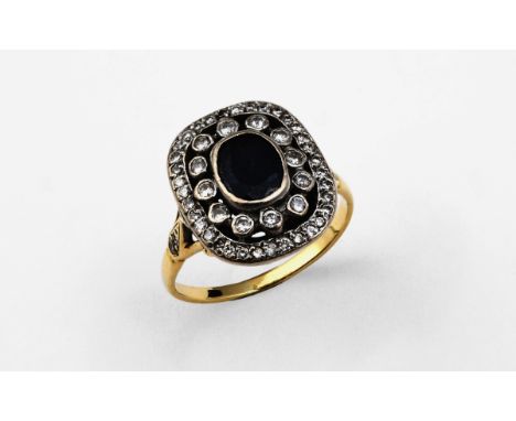 A SAPPHIRE AND DIAMOND CLUSTER RING the oval-shaped sapphire is set within a double surround of circular-cut diamonds, in gol