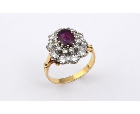 A RUBY AND DIAMOND CLUSTER RING the oval-shaped ruby is set within a double surround of circular-cut diamonds in yellow gold.