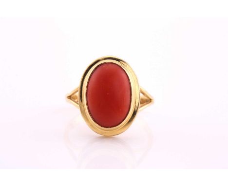 A coral cabochon ring, the 13.2 x 9mm oval cabochon to a yellow collet seIng and split shouldered shank, 18ct gold import mar