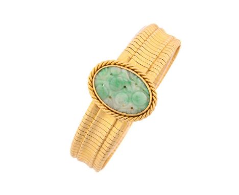 A Jade bracelet, the central oval carved jade panel within a ropetwist border, to a yellow precious metal flat articulated li