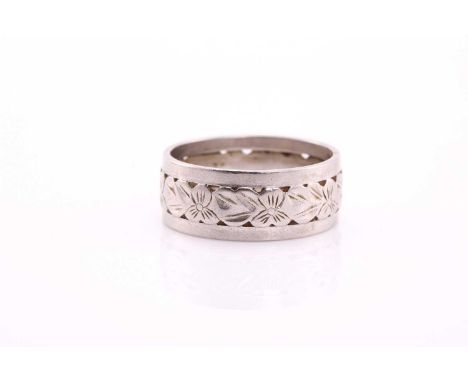A white precious metal wedding band, with central pierced and engraved floriate design, stamped 'PLAT S&W 40', 8mm deep, ring