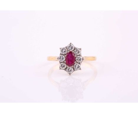 A ruby and diamond cluster ring; the oval cut ruby in six claw mount above a border of eight round brilliant cut diamonds, to