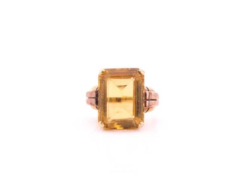 An Art Deco citrine dress ring, the rectangular step-cut citrine four claw set to a yellow mount with stylized knot shoulders