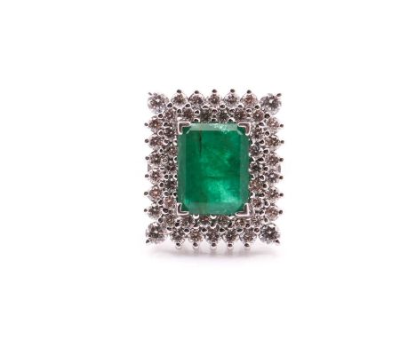 An emerald and diamond cluster ring, the rectangular step cut emerald within a two row surround of round brilliant cut diamon