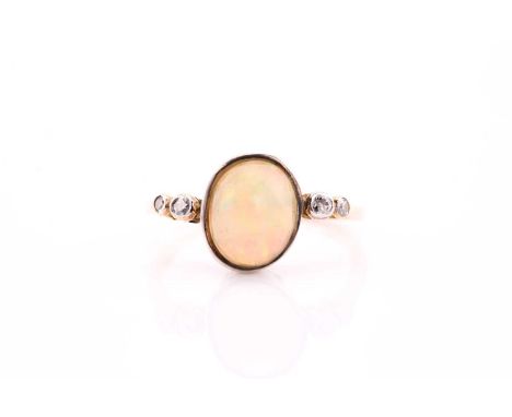 An opal and diamond ring, the oval cabochon opal,  approximately 12mm by 9.7mm, flanked by two mine cut diamonds to each shou