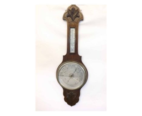 A first half of 20th Century Oak cased, Aneroid Wheel Barometer, the shaped case with applied carved foliate detail to a twin