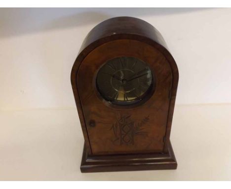 A Walnut cased Mantel Clock, the arched case with plinth base and hinged door carved with an hourglass, to an associated arch