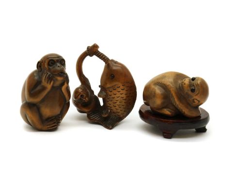 Three Japanese wood netsuke,20th century, signed, comprising:a monkey catching a fish,5.5cm high,a seated monkey,5cm high, wi
