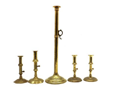 A tall brass candlestick,mid 18th century, with a brass slide ejector, 52cm high, and four further brass candlesticks with ej