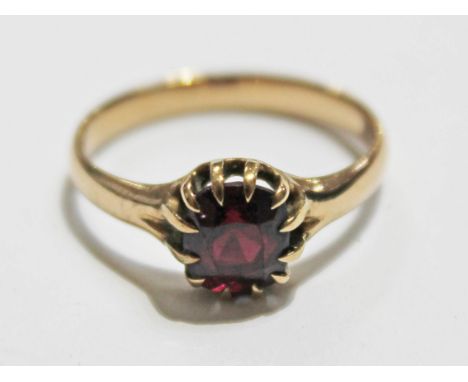 A yellow metal ring set with a garnet coloured stone, unmarked, gross wt. 2.3g, size M.