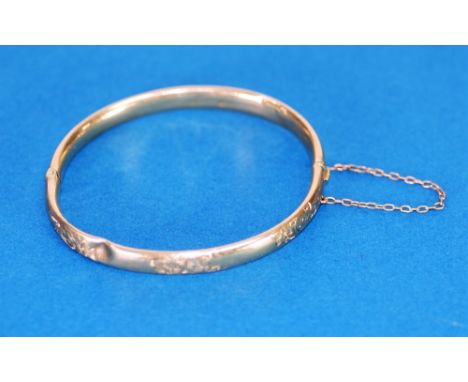 9ct GOLD HINGE OPENING HOLLOW BANGLE, the top engraved with foliate scrolls,                                        Birmingha