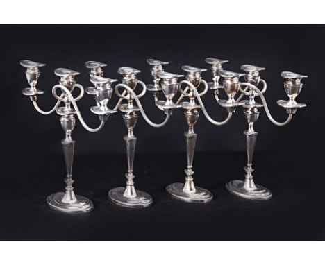 A SET OF FOUR ENGLISH SILVER-PLATED THREE LIGHT CANDELABRA
In George III style, with two winding branches and with urn-shaped