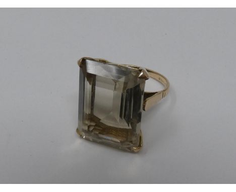 A 9ct yellow gold and citrine dress ring. Set with a rectangular mixed cut pale yellow stone in a four claw setting with an a