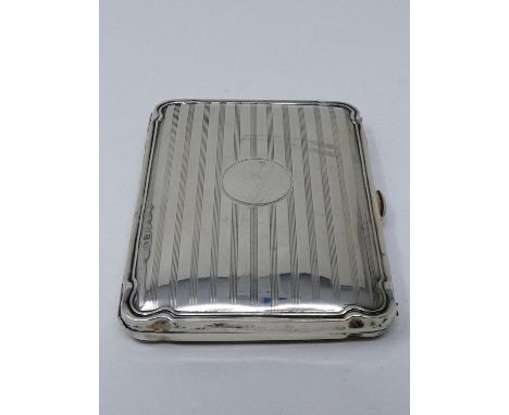 An leather lined Edwardian silver cigarette case with engine turned linear decoration, circular cartouche and scalloped corne