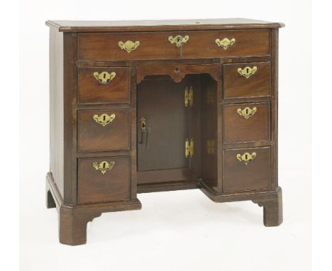 A George III mahogany kneehole desk, the canted cornered rectangular top above a frieze drawer and six further drawers, encom