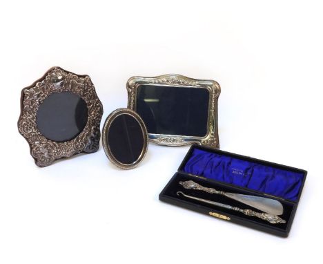 Three silver photo frames, together with a button hook, and shoe horn