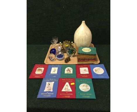 A tray of set of Beatrix Potter books, four glass paperweights, gilt cherub mantel clock, vase etc 