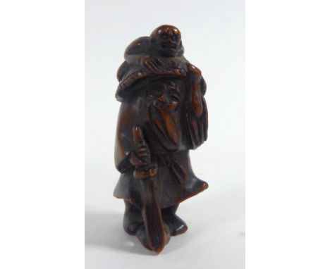 19th CENTURY JAPANESE CARVED WOODEN NETSUKE in the form of a bearded old man walking with a staff, wearing a large straw hat,